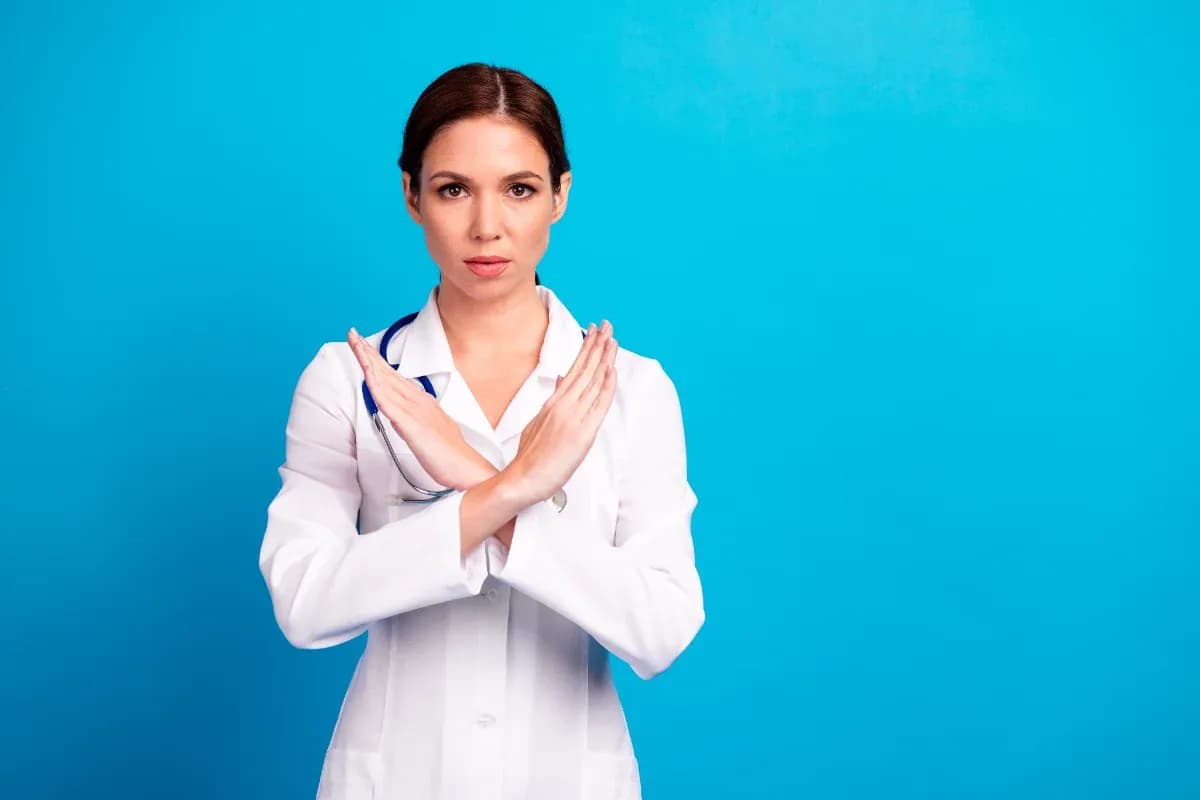 Cheerful doctor with crossed arms in a bright blue clinic setting delivers confident health care message