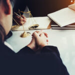 law and justice concept, client discussion lawyer judgement lawsuit with holding pen, law book,gavel and scales of justice at table in office. law and justice concept, client discussion lawyer judgement lawsuit with holding pen, law book,gavel and scales of justice at table in office.