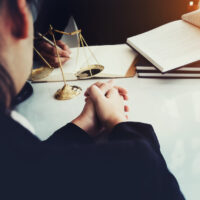 law and justice concept, client discussion lawyer judgement lawsuit with holding pen, law book,gavel and scales of justice at table in office. law and justice concept, client discussion lawyer judgement lawsuit with holding pen, law book,gavel and scales of justice at table in office.