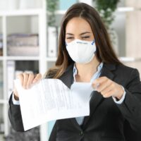 Executive wearing mask ripping contract at office Executive wearing mask ripping contract at office