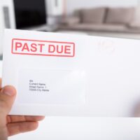 Person Holding Past Due Bill Envelope