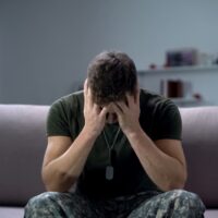 Nervous male military suffering depression, sitting alone at home, PTSD concept