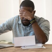 Stressed upset african american reading bad news in letter. Stressed upset african american reading bad news in letter.