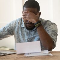 Stressed upset african american reading bad news in letter.