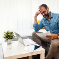 Confused frustrated mature man holding mail letter and money, re Confused frustrated mature man holding mail letter and money, re