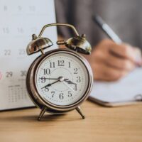 due date calendar with alarm clock on office desk and blur busin due date calendar with alarm clock on office desk and blur busin