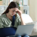 Worried handicapped woman reading news on laptop