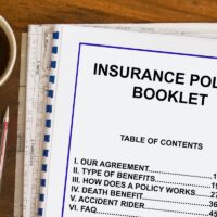 Insurance policy booklet with coffee and documents concept.