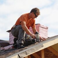 Building contractor putting the asphalt roofing on a large commercial apartment building development