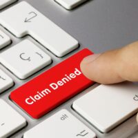 Claim Denied Written on Red Key of Metallic Keyboard. Finger pressing key. Claim Denied Written on Red Key of Metallic Keyboard. Finger pressing key.