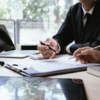 Close up of male lawyer working with contract documents and wooden hammer on table in courtroom. Justice and law. Judge in suit or lawyer working with documents. Law. Close up.