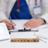 A healthcare professional performing a health screening with medical devices and necessary paperwork