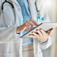 Doctor, office and tablet for research, email or communication. Medic, hospital and reading article, data or health magazine on web, while working with technology in healthcare center or clinic.