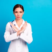 Cheerful doctor with crossed arms in a bright blue clinic setting delivers confident health care message
