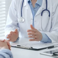 Female doctor explaining diagnosis to her patient during a medical consultation in a bright medical office, healthcare and medical concept. Medicine and health care concept